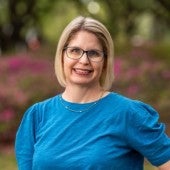 Photo of Brandy McDaniel in a puffy sleeved shirt in front of Rice's azalea bushes